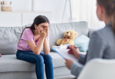 Depresyondaki Hintli genç kız ofiste psikologla görüşüyor, yüzünü gizliyor, sorunlardan bahsediyor.