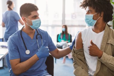 Aşılanmış Siyahi Adam ve Doktor Klinikte Başparmak İşaret Ediyor
