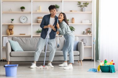 Komik Asyalı çift daireleri temizlerken şarkı söylüyor, boşluğu kopyala