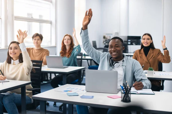 Retrato de diversos estudiantes levantando las manos en el aula moderna — Foto de Stock