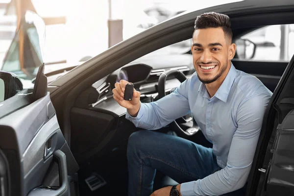 Bello arabo uomo cliente seduto in auto e tenendo chiave — Foto Stock