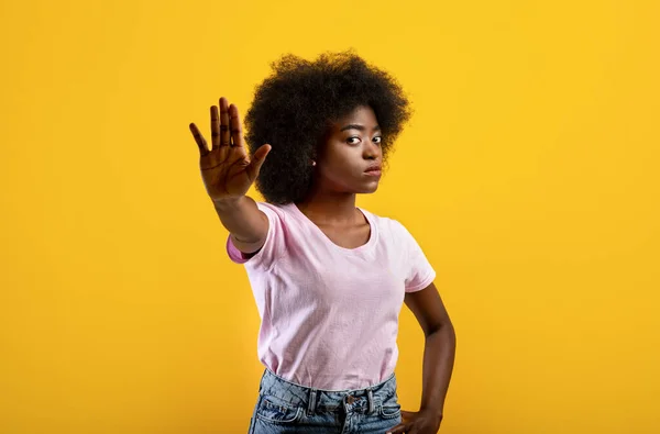 Afro-Amerikaanse dame gebaren STOP, tonen afwijzing gebaar op gele studio achtergrond — Stockfoto