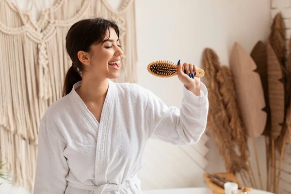 Side-view van Brunette vrouw zingen poseren met haarborstel in de badkamer — Stockfoto