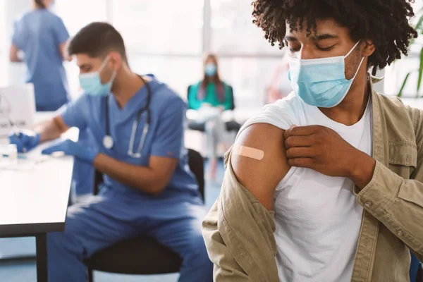 Zwarte man toont gevaccineerde arm met lijm verband in het ziekenhuis — Stockfoto