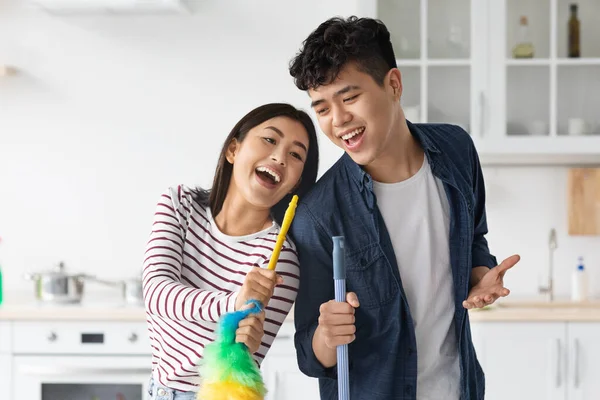 Emocional asiático hombre y mujer cantando mientras limpieza cocina — Foto de Stock