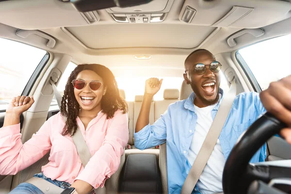 Glückliches schwarzes Paar mit Sonnenbrille genießt Musik am Steuer eines Luxusautos — Stockfoto
