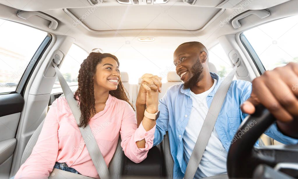 Happy black couple enjoying drive on car, holding hands