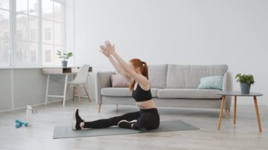 Spor salonundaki kadın egzersiz yapıyor. Evde, yerde oturuyor.