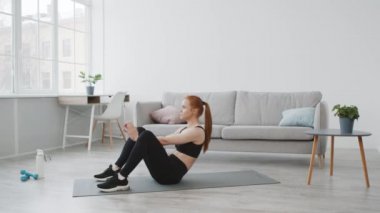 Spor kadın mekik çekiyor, karın kaslarını kasıyor evde egzersiz yapıyor.