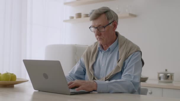 Ηλεκτρονική εκπαίδευση για ηλικιωμένους. Εντοπισμός στιγμιότυπου συμπυκνωμένου ηλικιωμένου άνδρα σε φορητό υπολογιστή στην κουζίνα — Αρχείο Βίντεο