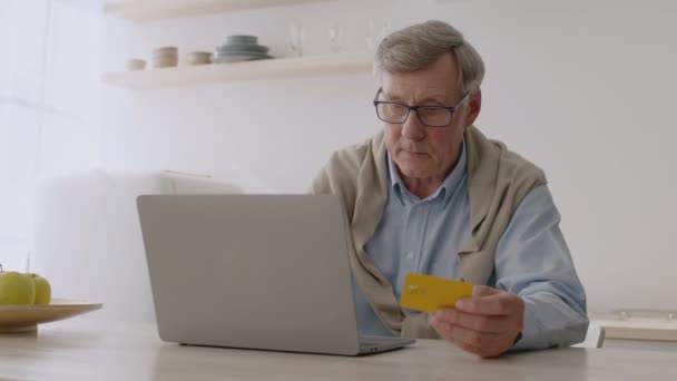 Senior wprowadzający informacje z karty kredytowej na stronę internetową na laptopie i korzystający z technologii internetowych — Wideo stockowe