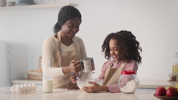 Positivo afro-americano mãe e filha vestindo aventais cozinhar itens de cozimento juntos, preparando massa — Vídeo de Stock