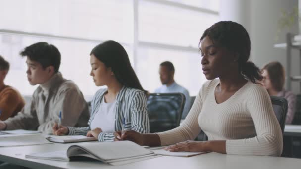 Grupo de jóvenes estudiantes universitarios multiétnicos tomando notas, sentados juntos y en clase durante la conferencia, cámara lenta — Vídeos de Stock