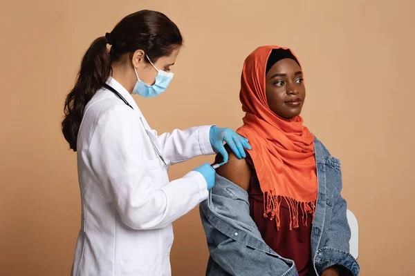 Mulher negra muçulmana no hijab sendo vacinada, fundo de estúdio — Fotografia de Stock