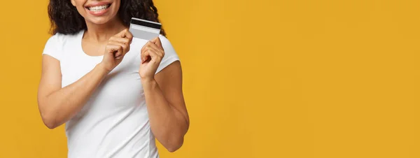 Concept de paiement numérique. Femme méconnaissable tenant et montrant carte de crédit de débit en plastique sur fond jaune — Photo