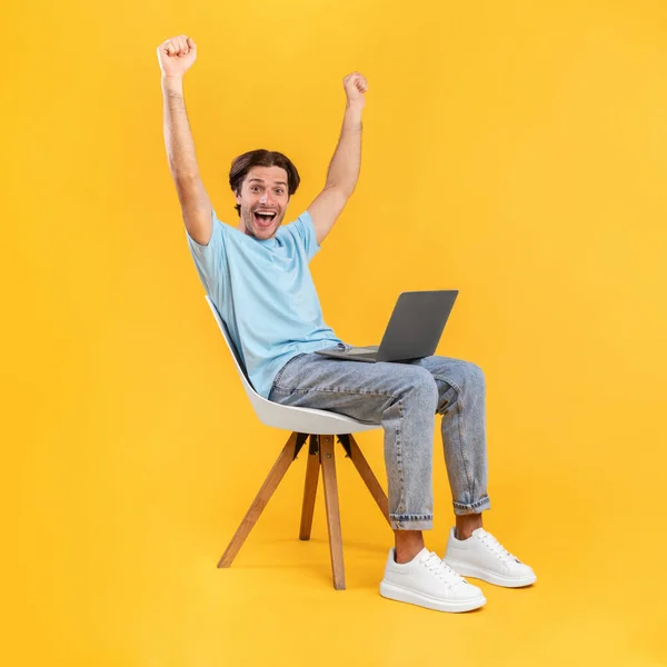 Heyecanlı adam dizüstü bilgisayar kullanarak yumruk sallamayı kutluyor. — Stok fotoğraf
