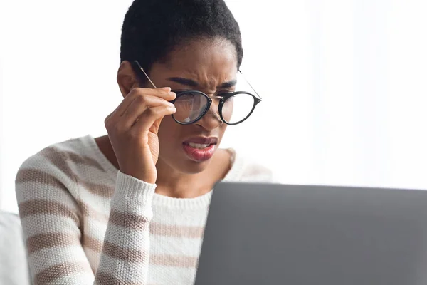 Slecht gezichtsvermogen concept. Afro-Amerikaanse dame in brillen op zoek naar laptop scherm — Stockfoto