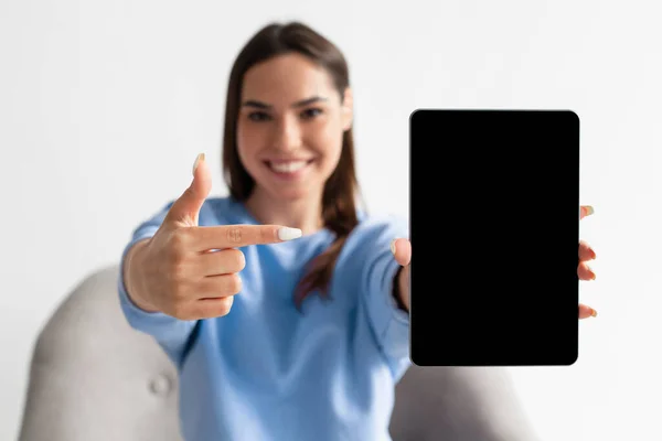 Giovane donna gioiosa che punta al tablet con schermo bianco per il mockup, promuovendo la nuova app, offrendo spazio per il sito Web — Foto Stock
