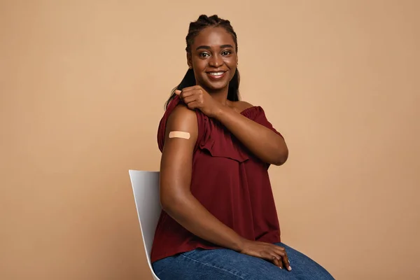 Felice signora nera mostrando spalla dopo la vaccinazione — Foto Stock
