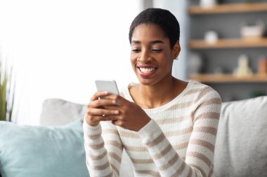 Mobil İletişim. Olumlu Genç Siyahi Kadın Evde Akıllı Telefonla Mesajlaşıyor