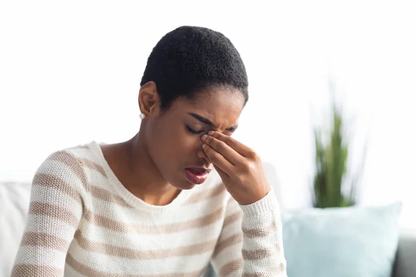 Sinusitis Konzept. Kranke junge schwarze Frau berührt ihre Nasenbrücke zu Hause — Stockfoto