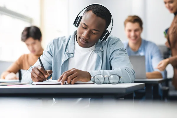 Homme noir assis au bureau en classe examen d'écriture — Photo