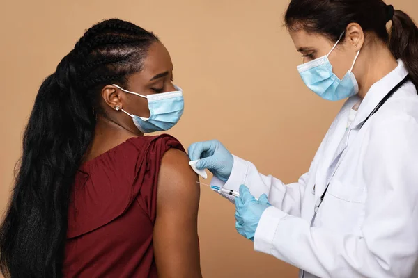 Jovem enfermeira fazendo injeção para mulher negra — Fotografia de Stock