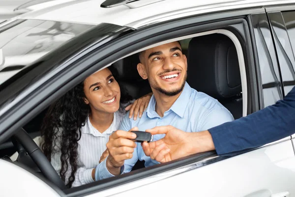 Happy middle-eastern couple sitting in car in huge showroom — Stock Photo, Image