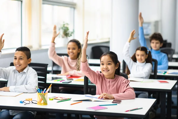 Diverse groepen kleine schoolkinderen steken de handen uit de mouwen in de klas — Stockfoto