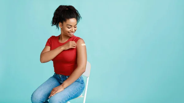 Молода чорна жінка після імунізації ковадла-19 демонструє плече за допомогою смуги, сприяє вакцинації, вільний простір — стокове фото