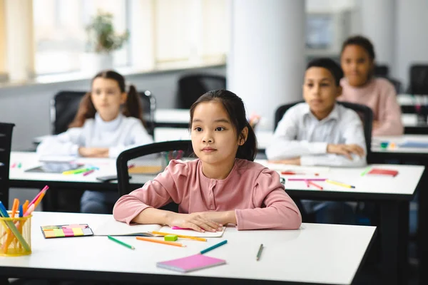 Portret van gefocust aziatisch meisje zittend aan een bureau in de klas — Stockfoto