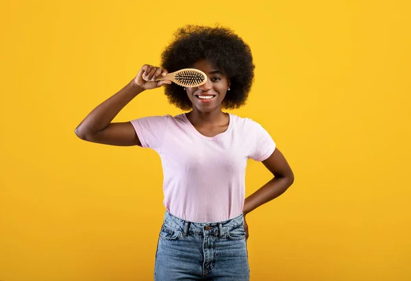ヘアケアの概念。幸せなアフリカ系アメリカ人若いです女性とともに忙しい髪カバー目で毛ブラシ,黄色の背景 — ストック写真