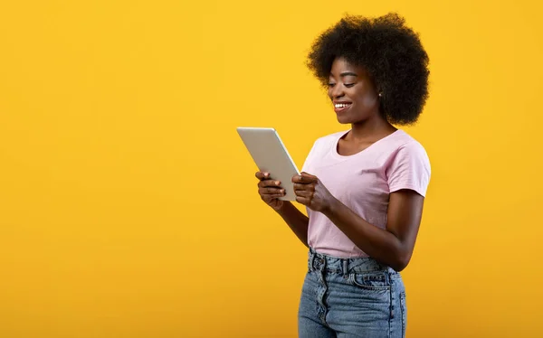 Technológia és kommunikáció. Boldog fekete fiatal nő kezében digitális tabletta, sárga háttér, szabad hely — Stock Fotó