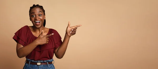 Renkli arkaplanda poz veren siyah kadın, fotokopi alanını işaret ediyor. — Stok fotoğraf