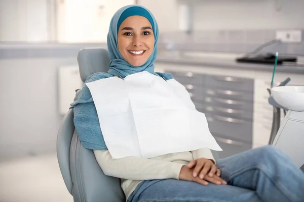Retrato de uma paciente muçulmana feliz sentada na cadeira na clínica dentária — Fotografia de Stock