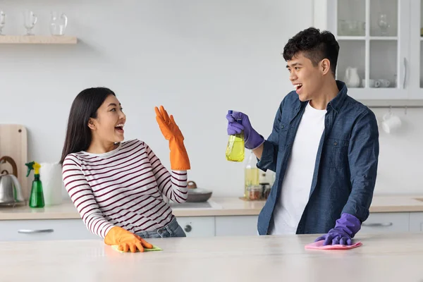 Joyful asiático amantes se divertindo enquanto limpeza cozinha juntos — Fotografia de Stock