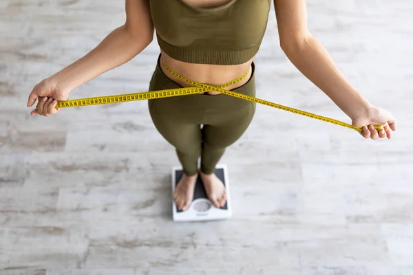 Nahaufnahme einer indischen Frau, die Taille misst, auf einer Waage steht, das Ergebnis der Gewichtsabnahme überprüft und Körperparameter misst — Stockfoto