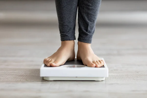 Femme indienne méconnaissable debout sur des balances, vérifiant son poids à l'intérieur, gros plan des pieds — Photo