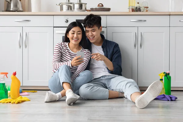 Cansado asiático hombre y mujer sentado en el suelo, usando el teléfono — Foto de Stock