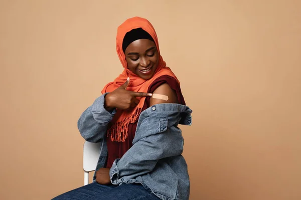 Mulher africana feliz em hijab olhando para gesso no braço — Fotografia de Stock