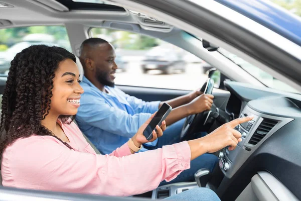 Glückliches schwarzes Paar fährt Auto und benutzt Handy — Stockfoto