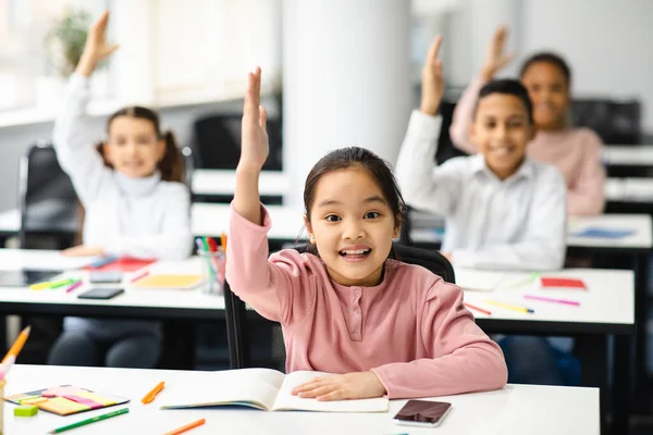Portrait of little school children raising hands at classroom — Stock Photo, Image
