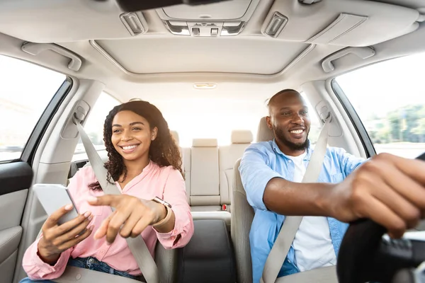 Feliz pareja negra conduciendo coche y usando el teléfono celular —  Fotos de Stock