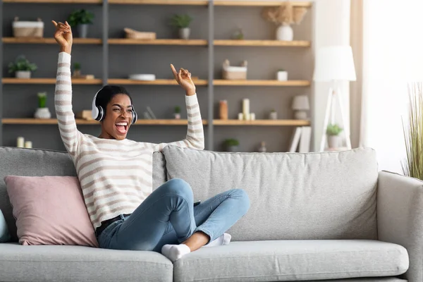 Αγαπημένο τραγούδι. Χαρούμενη νεαρή μαύρη γυναίκα ακούγοντας μουσική στα ακουστικά στο σπίτι — Φωτογραφία Αρχείου