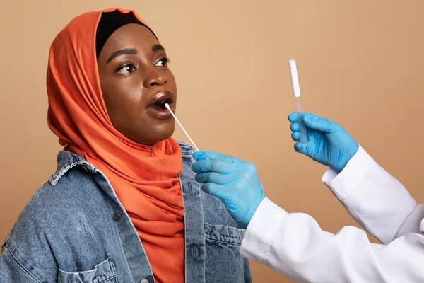 Enfermeira a tomar cotonete oral para amostra de coronavírus de mulher muçulmana — Fotografia de Stock