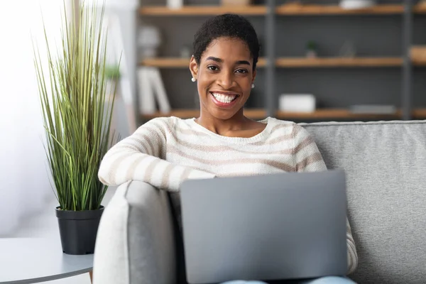 Porträtt av glada afroamerikanska Lady koppla av med laptop på soffan hemma — Stockfoto