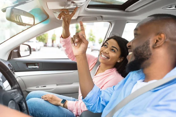 Feliz negro pareja sentado en coche pulsando botones — Foto de Stock