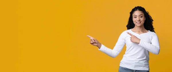 Возбужденная афроамериканка, указывающая на копировальное пространство двумя руками — стоковое фото