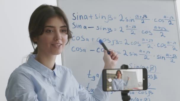 Blog útil para adolescentes. Jovem mulher inteligente gravação de vídeo no smartphone, explicando fórmulas matemáticas — Vídeo de Stock