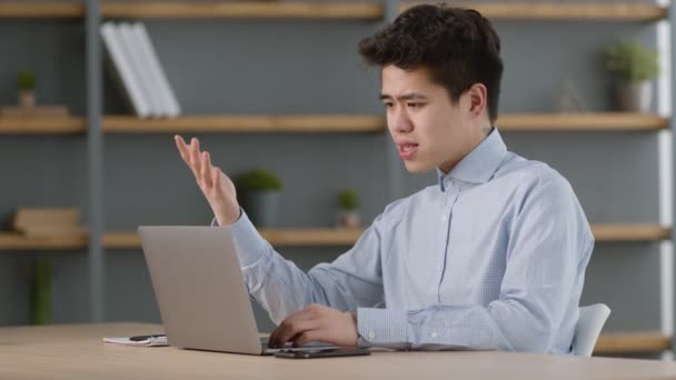Jonge Aziatische kantoormedewerker videoconferentie met buitenlandse partners via laptop chat, zitten op gezellig kantoor, vrije ruimte — Stockvideo